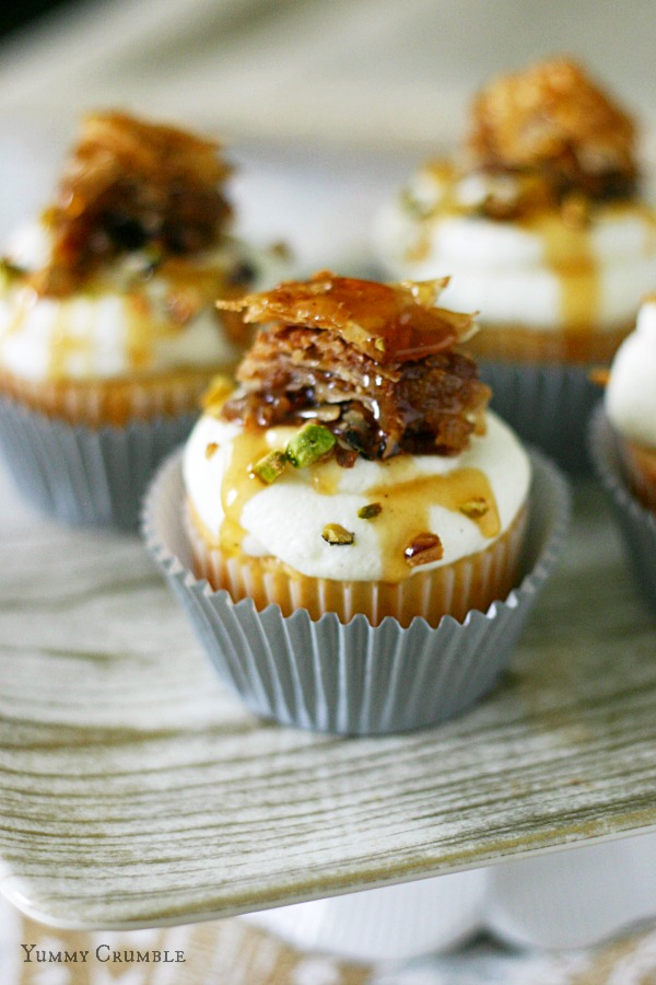 Baklava honey cupcakes with mascarpone whipped frosting and topped with a slice of baklava, pistachios, and honey drizzle - www.yummycrumble.com